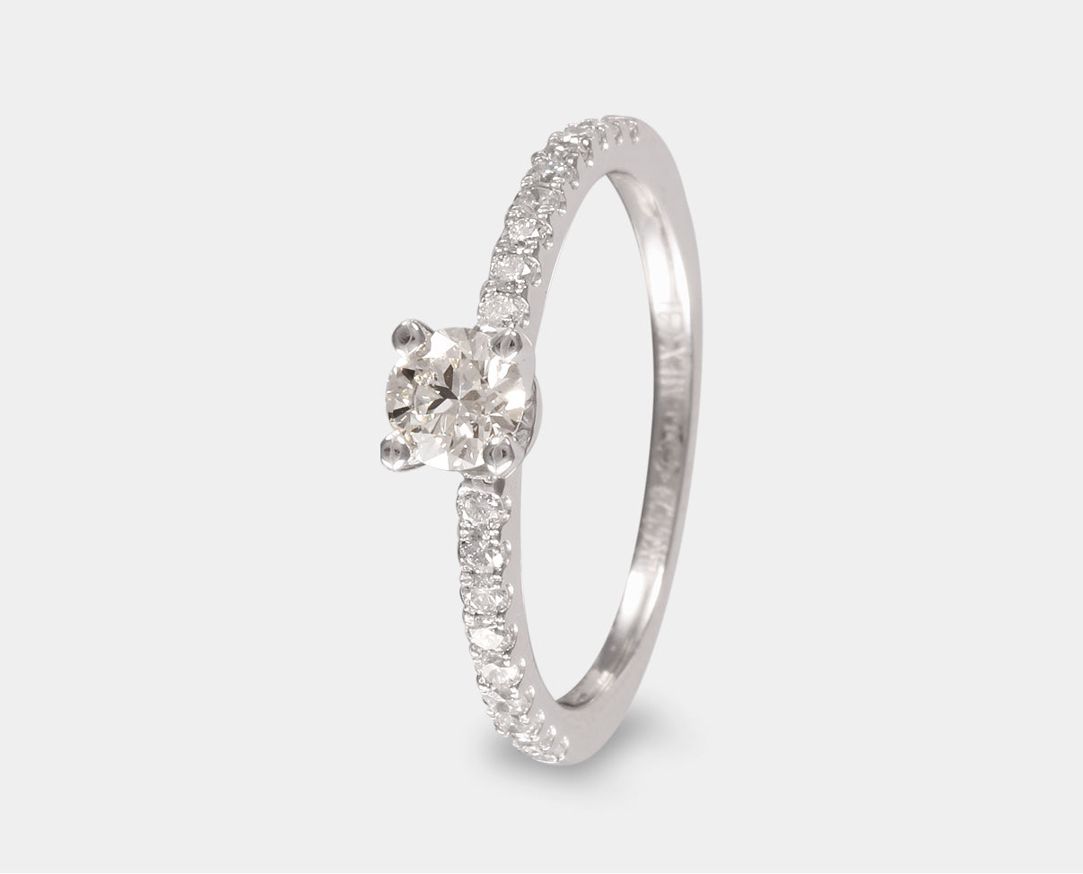 Anillo de Compromiso con diamante central corte brillante y diamantes laterales en oro blanco de 14k. Anillo con diamantes laterales. 