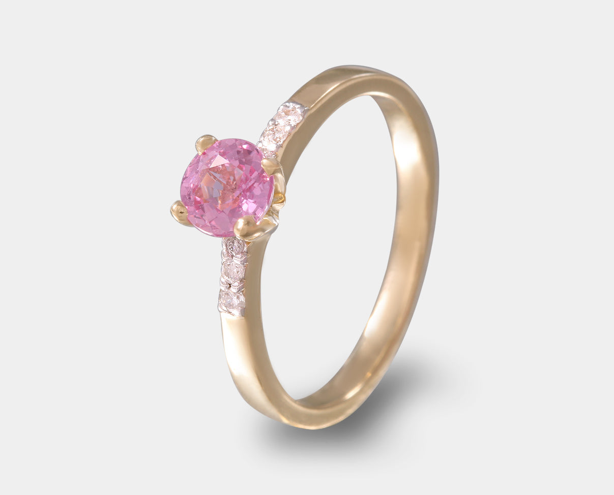 anillo de compromiso con zafiro rosa y diamentes laterales